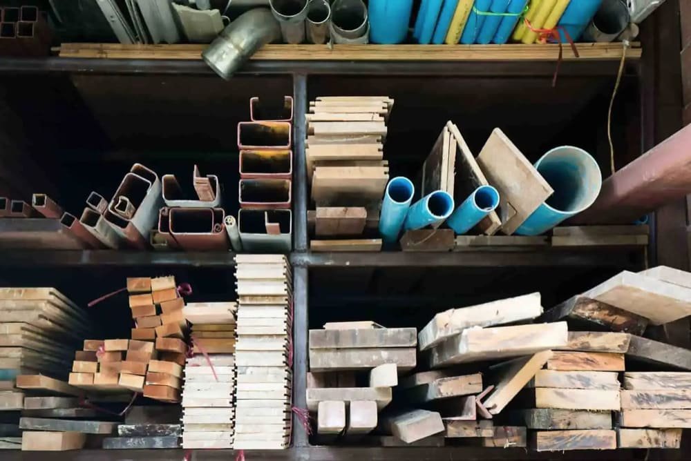 Shelves with metal and plastic pipes above wooden planks.