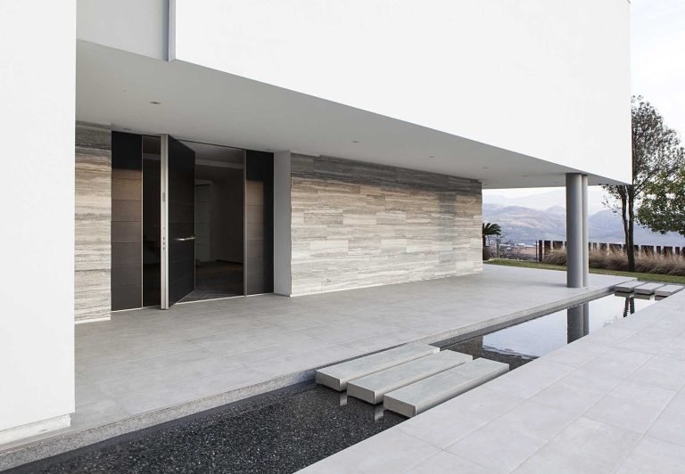 Modern minimalist house entrance with dark door and stone wall