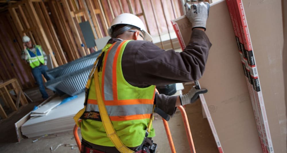 Workers installing drywall in framed interior