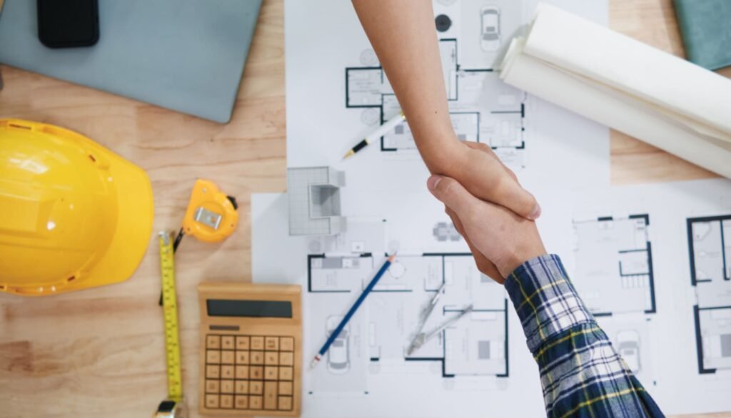 Signing construction contract handshake over blueprints