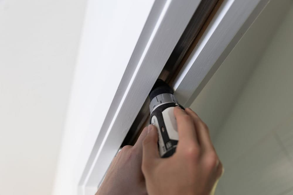 Hands using a cordless drill fixing sliding door frame