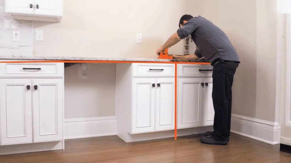 Person measuring kitchen cabinets with orange level tool