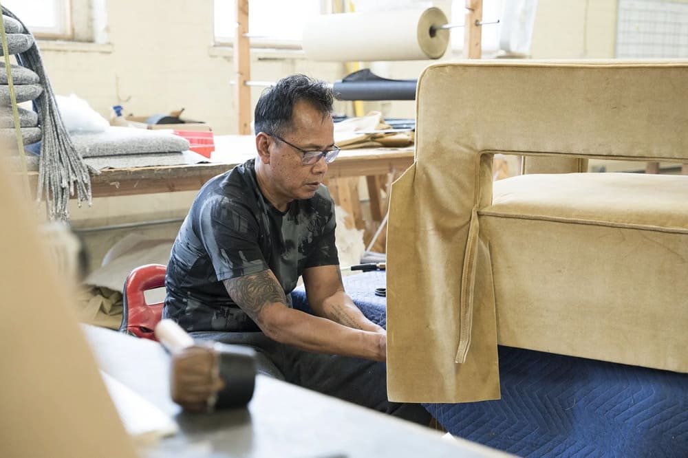 Upholstery craftsperson working on custom seating in a furniture factory