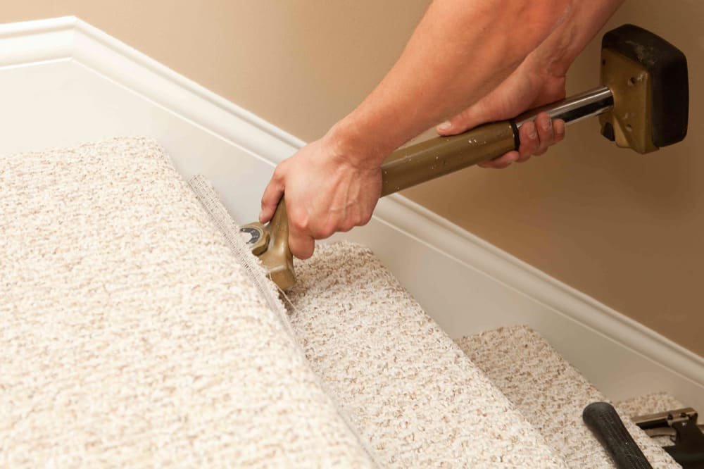 Person using a knee kicker to install carpet on a staircase