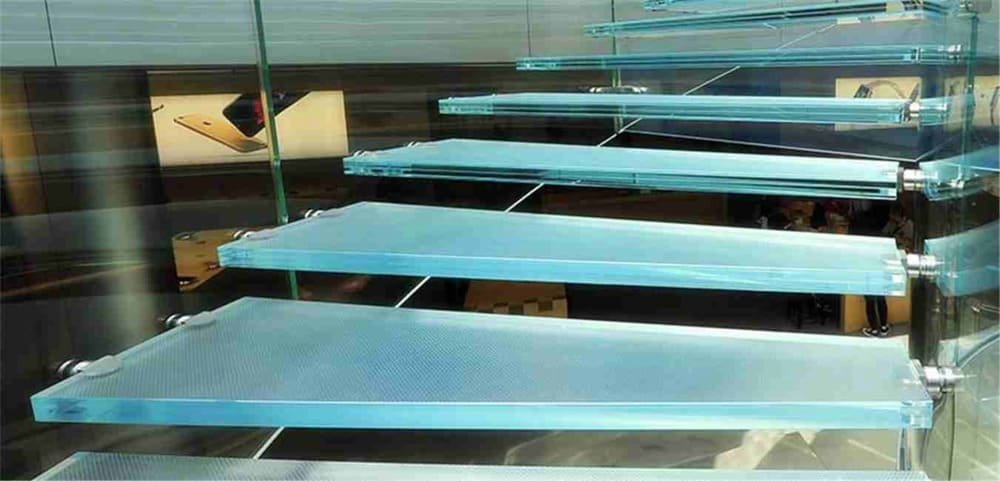 Glass stairs with bluish tint in a modern, high-tech setting with posters of electronic devices in the background