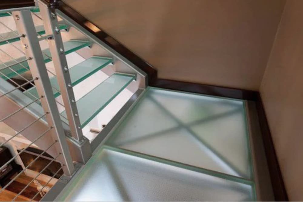 Glass stairway with metal railing and frosted glass floor panel