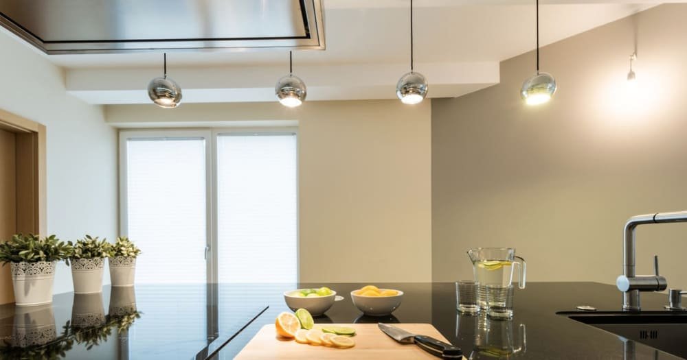 Modern kitchen with pendant lights, a black countertop, sliced lemons, and decorative plants
