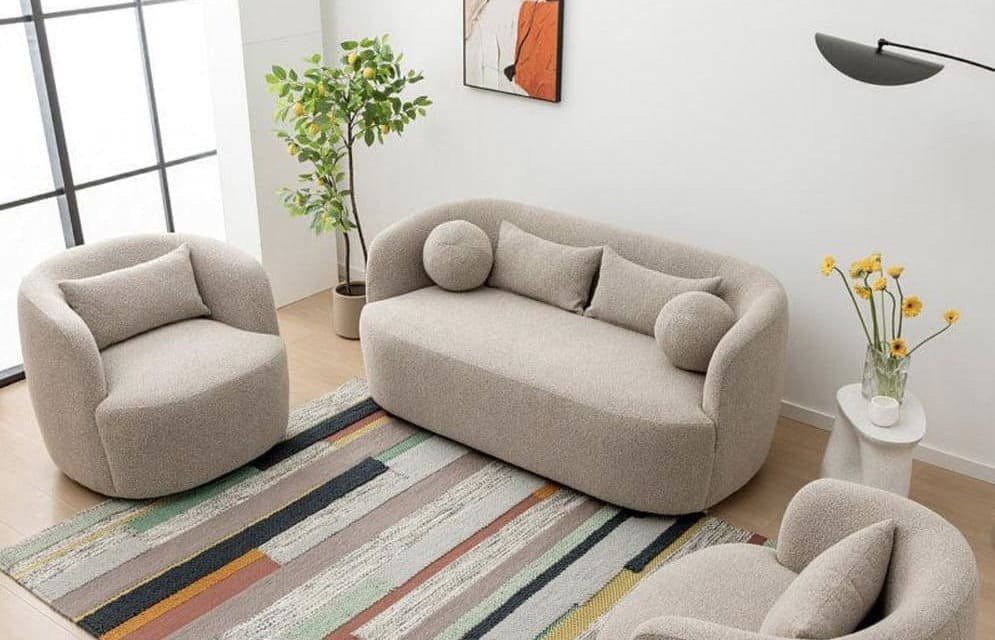 A modern living room with a beige sofa, armchair, multicolored rug, and decorative accents