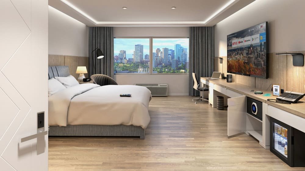 A modern hotel room with a bed, large window with city view, desk, and mounted flat-screen TV